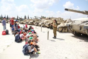 ילדים מקשיבים להדרכה של חיילת על טנקים 