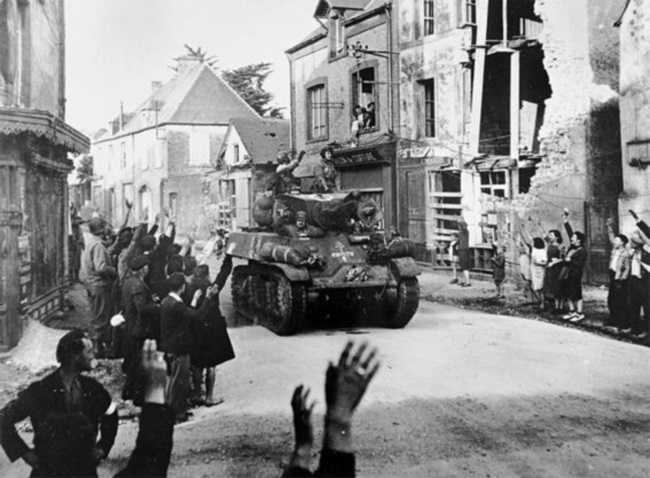 6 ביוני 1944: תושבי Sainte-Mère-Église מקבלים בחום טור שריון צרפתי העובר ביישוב